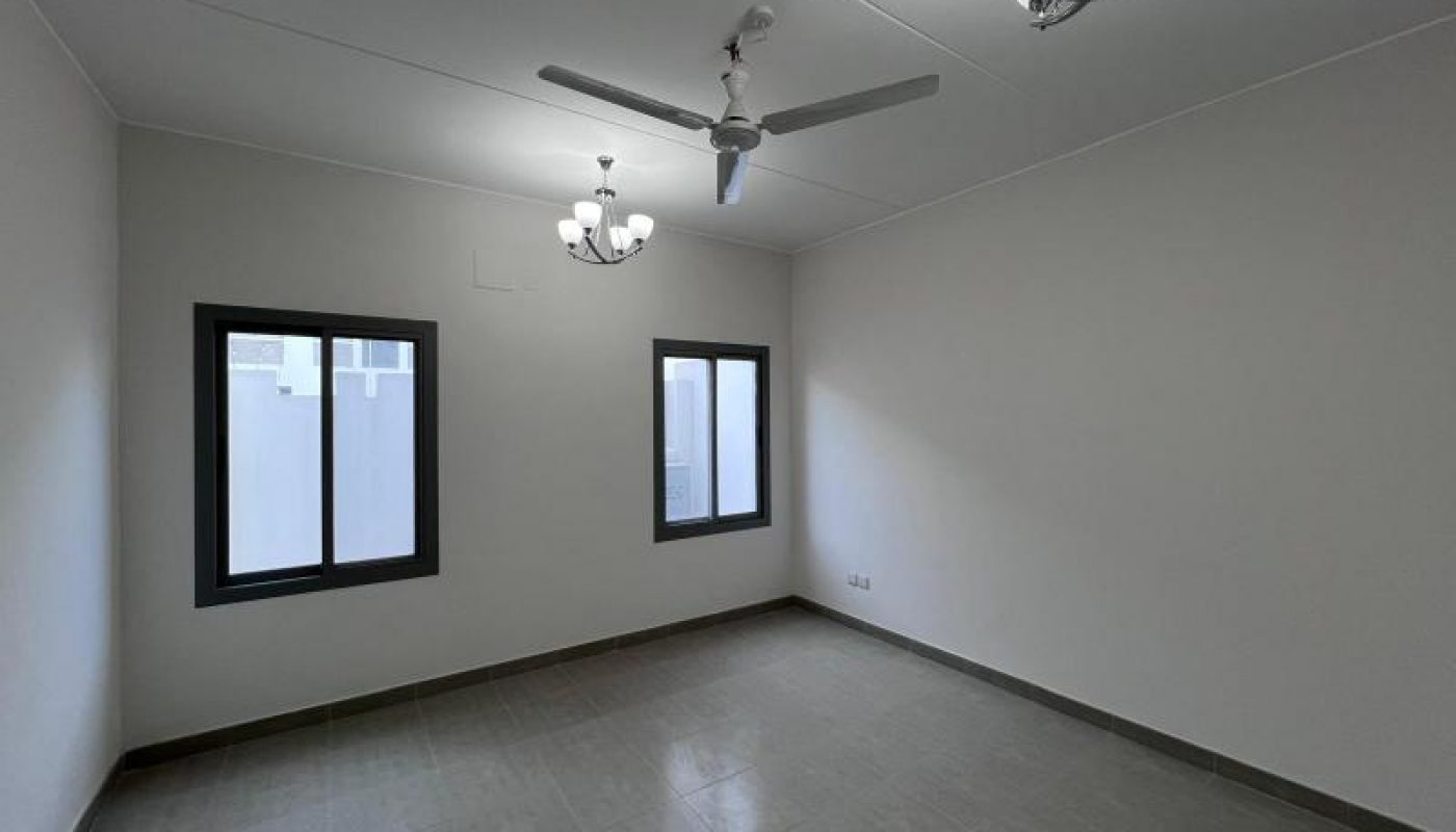 Empty, unfurnished room with two windows, a ceiling fan, two light fixtures, tiled floor, and white walls.