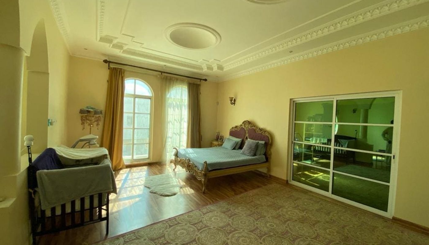 A furnished bedroom with a bed and a glass door.