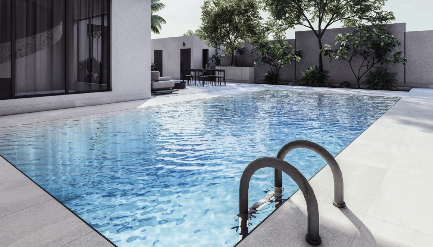 Modern outdoor swimming pool with clear water, stainless steel ladder, and surrounding patio area; trees and seating area visible in the background.