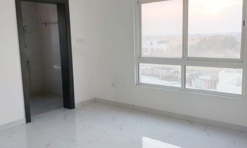 An empty room with a window and white tile floor, featuring a draft from the open window.