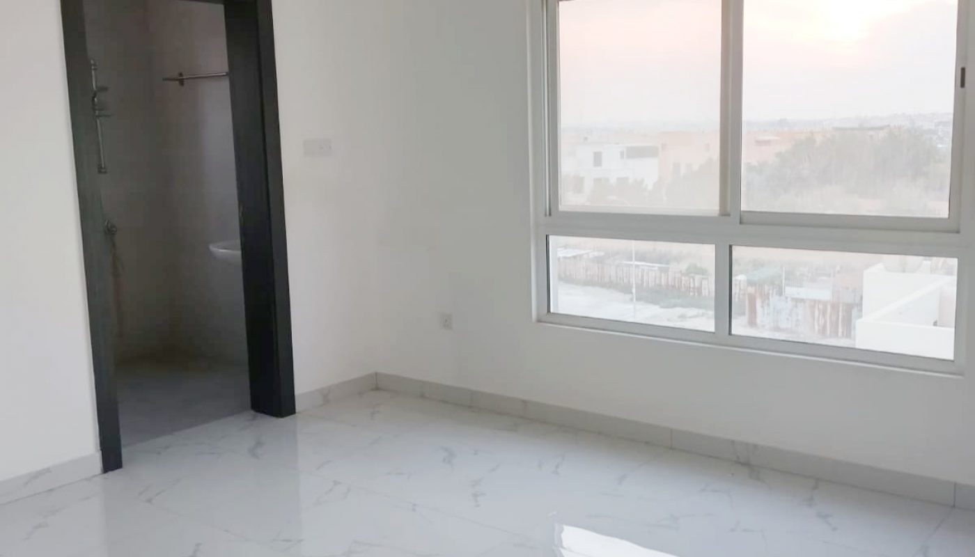 An empty room with a window and white tile floor, featuring a draft from the open window.