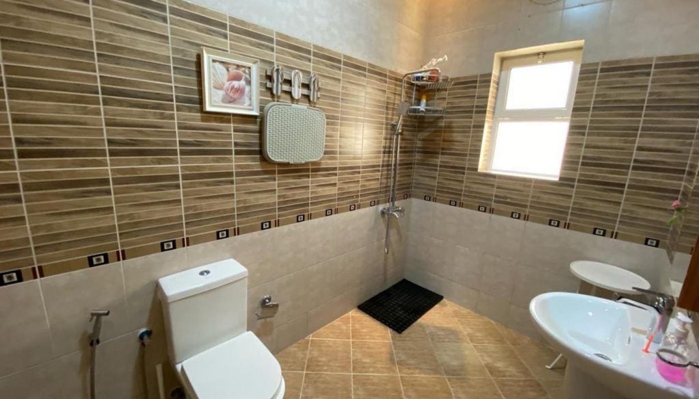 A villa in Galali with tiled walls and a toilet available for rent.