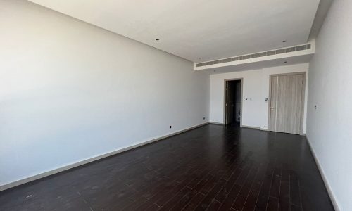 A spacious room with wooden floors and white walls.