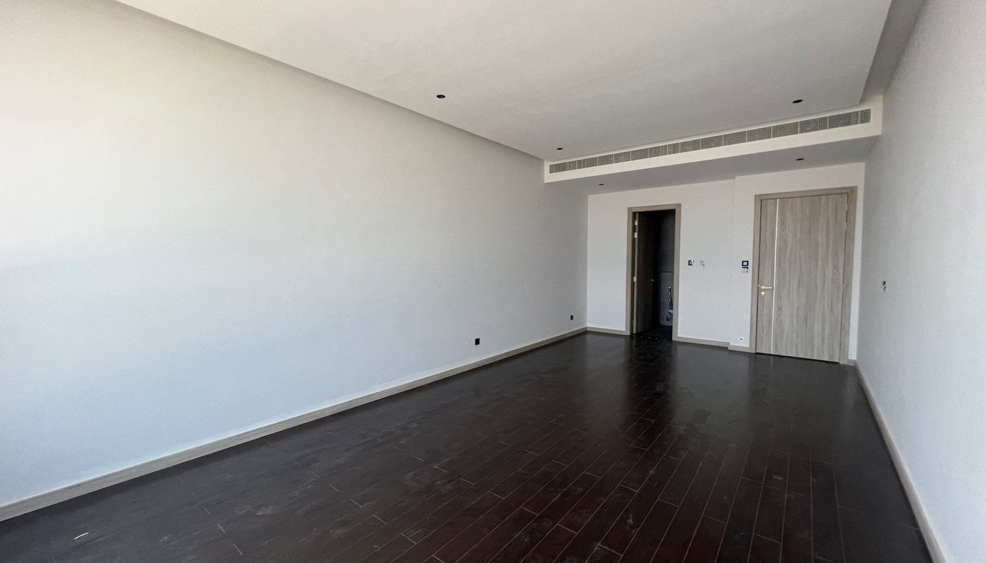 A spacious room with wooden floors and white walls.