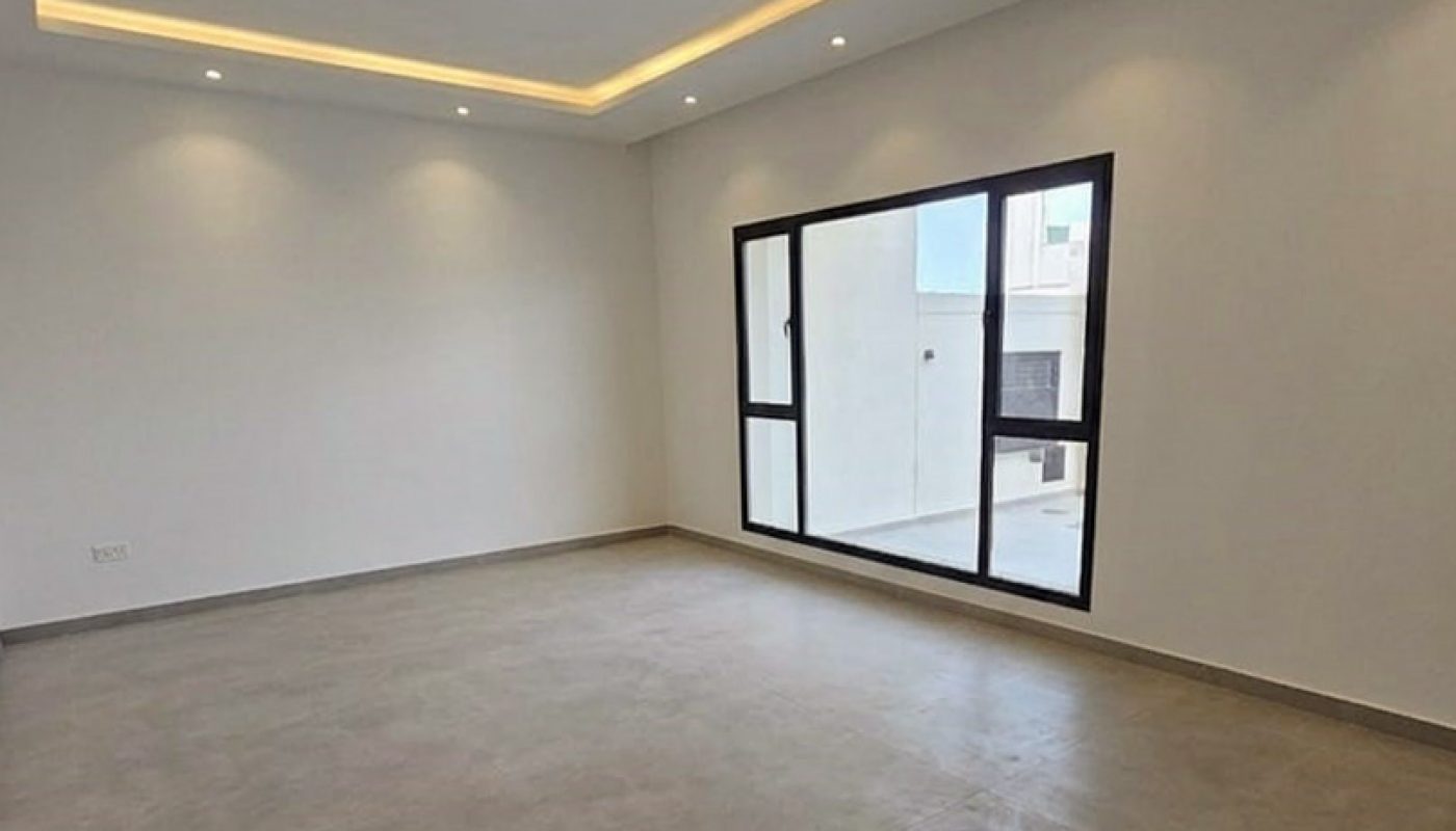 Empty room with tiled floor, white walls, recessed ceiling lights, LED strip lighting, and a large window letting in natural light.