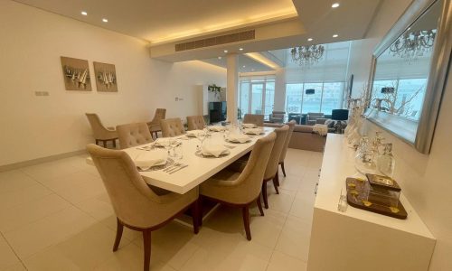 A neatly arranged dining room with a set table, comfortable chairs, and modern decor, featuring an Auto Draft system.