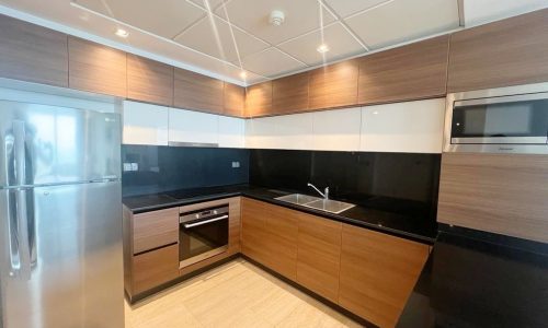 A luxury kitchen with wooden cabinets and stainless steel appliances in a Delmunia 2 bedroom.