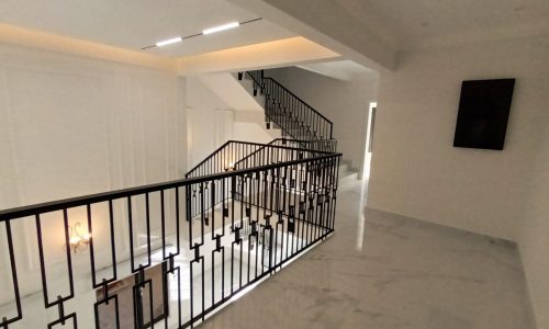 A spacious villa with a white staircase and white railings.