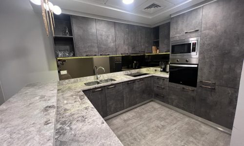 A luxury kitchen with grey cabinets and granite counter tops.