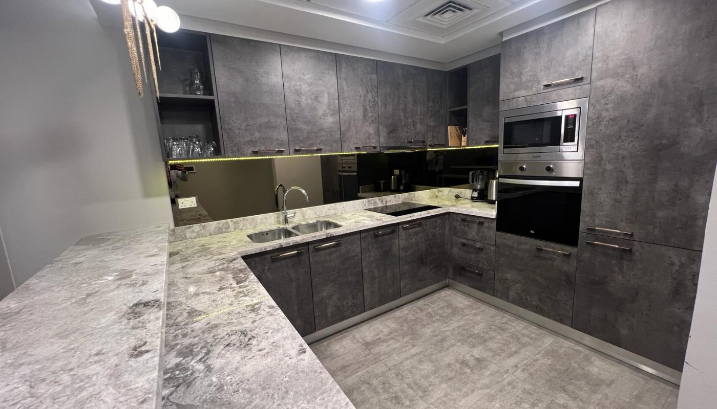 A luxury kitchen with grey cabinets and granite counter tops.