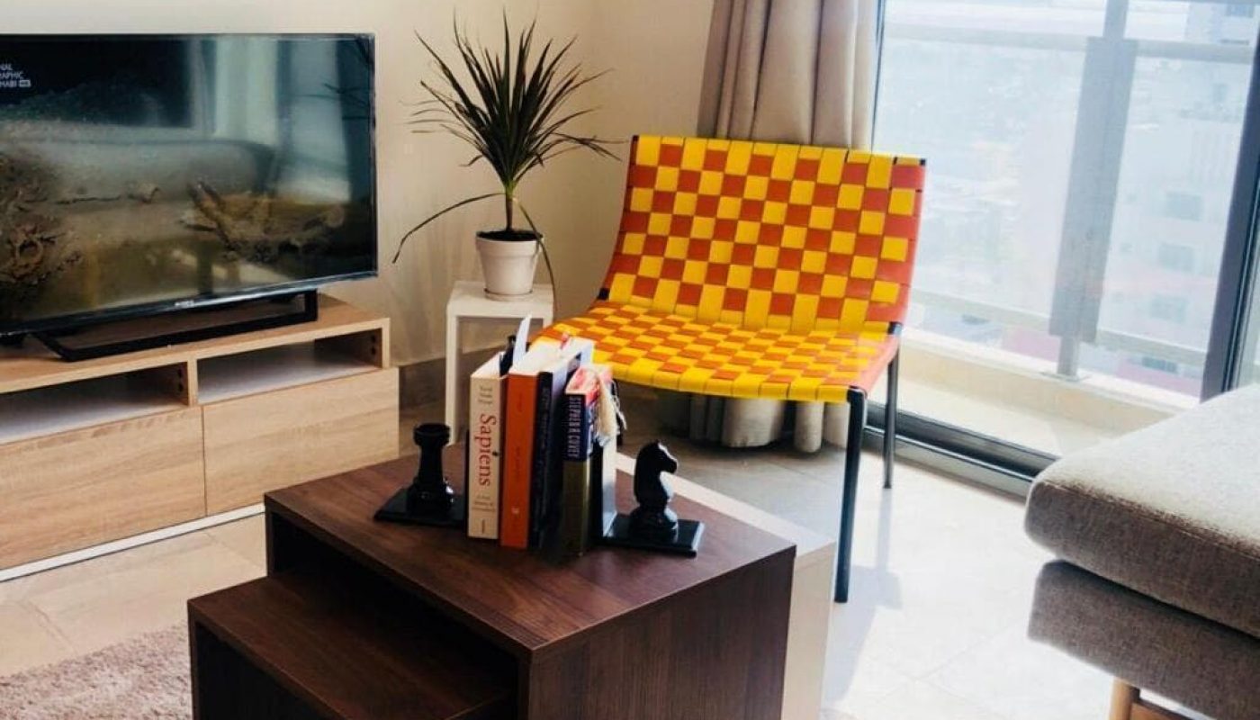 Luxury Apartment for Sale in Busaiteen: A spacious living room featuring a stylish tv and a comfortable chair.