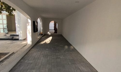 A spacious hallway leading to a luxurious white house with arches.