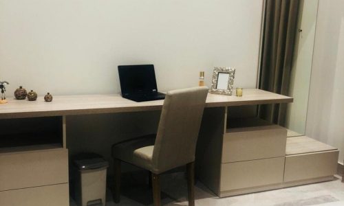 A luxury apartment in Busaiteen for sale. The apartment includes a bedroom with a desk, chair, and mirror.