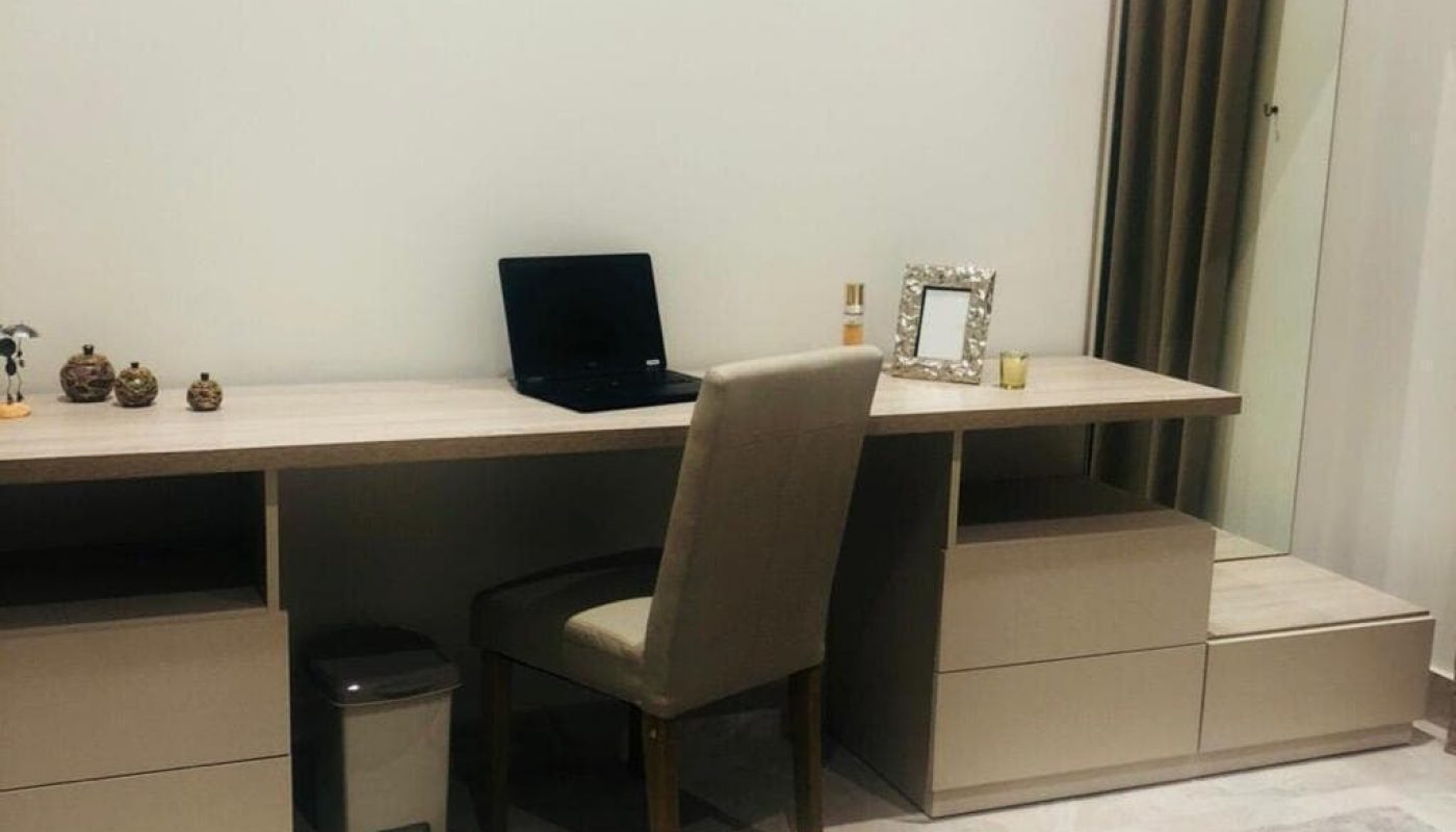 A luxury apartment in Busaiteen for sale. The apartment includes a bedroom with a desk, chair, and mirror.