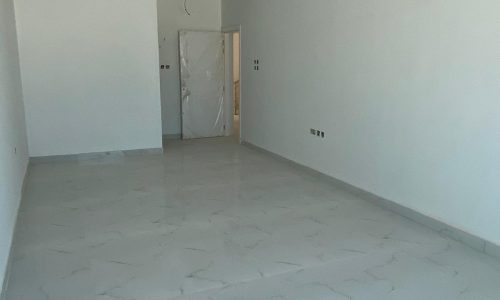 An empty room with white walls and tile floors offering amazing villas for sale in Durrat Al Muharraq with a 3-year guarantee.