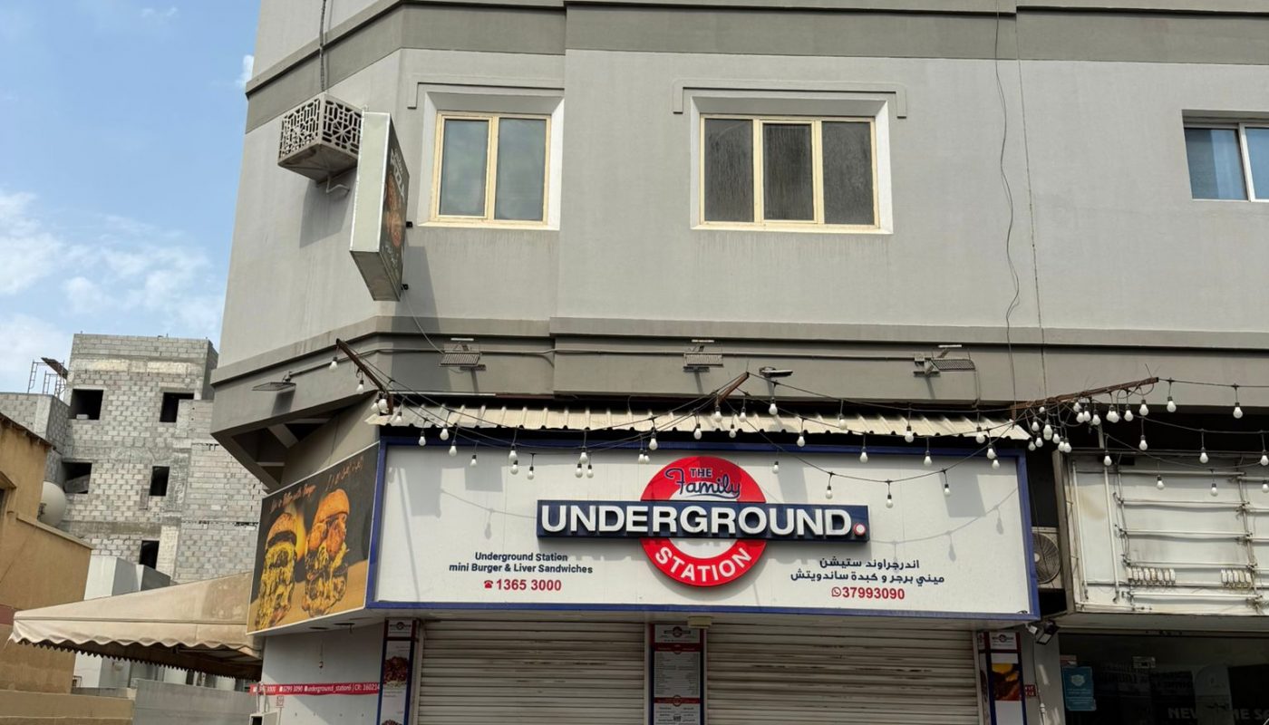 A gray two-story building with a closed shop named "Underground Station" on the ground floor, located on a quiet street corner under a partly cloudy sky.