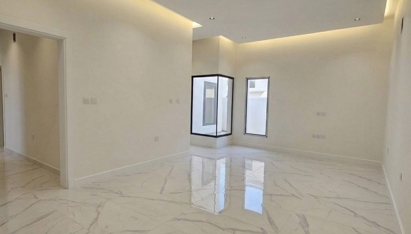 Empty modern room with large white marble floor tiles, recessed ceiling lights, and windows letting in natural light.