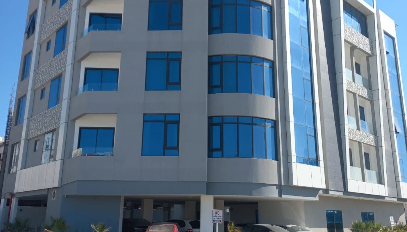 A Seef apartment building with cars parked in front of it available for sale.
