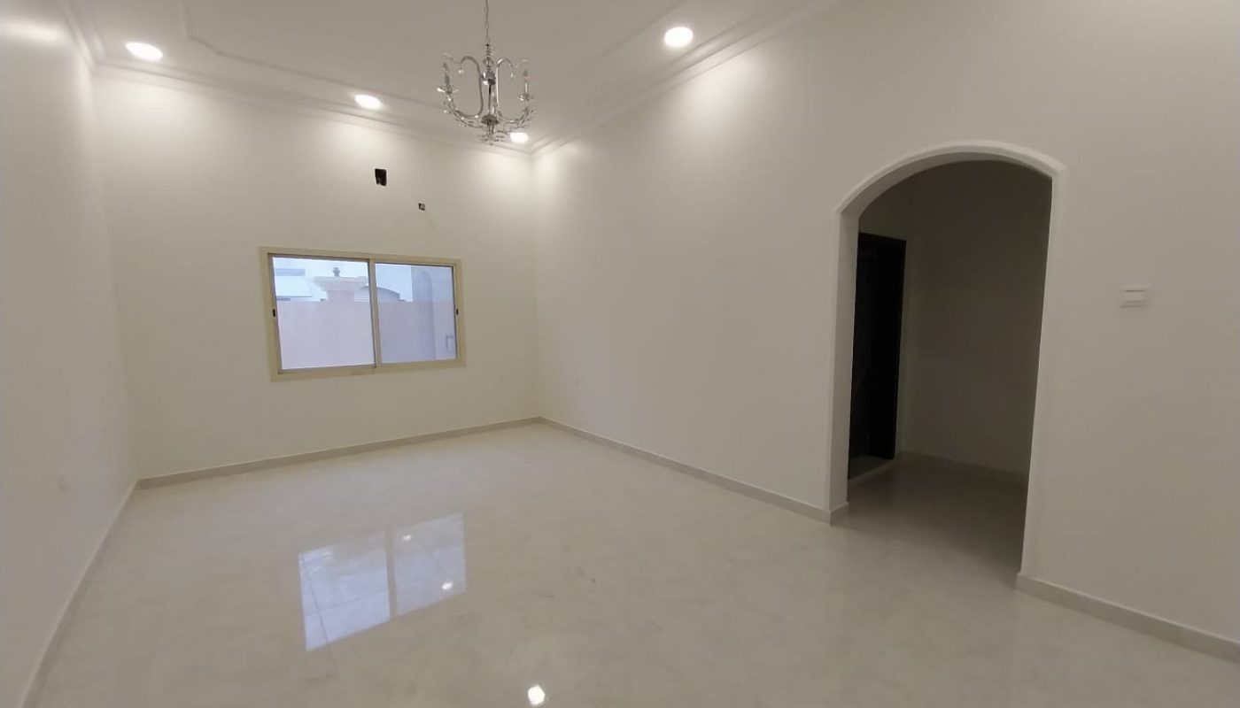 Empty room with white walls, tiled floor, a window on the left wall, a chandelier on the ceiling, recessed lighting, and an arched doorway on the right.