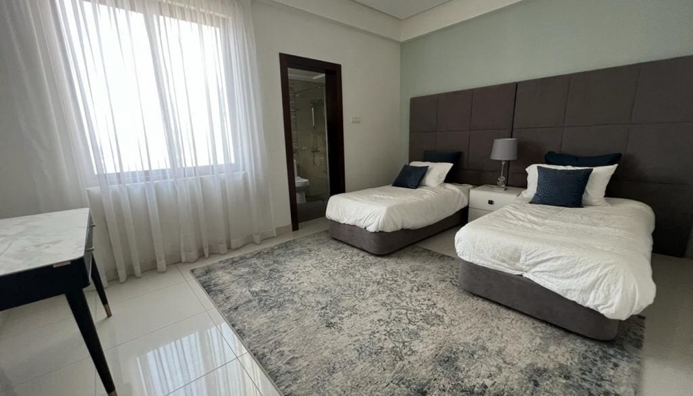 New bedroom with two beds and a desk in a luxury villa for sale in Hidd, featuring a balcony.