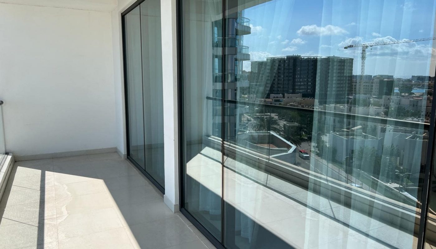 A balcony with glass sliding doors and a view of the city.