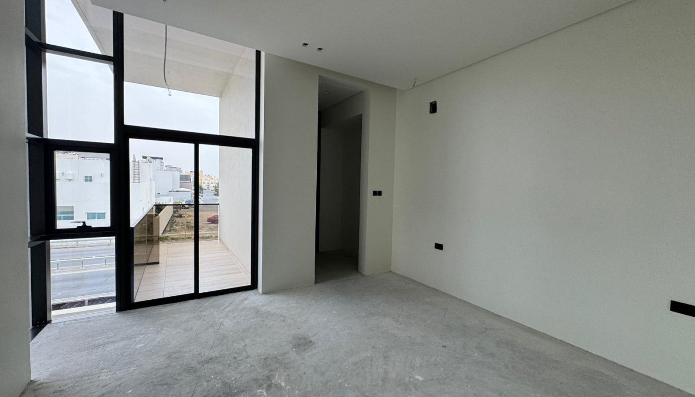 Unfurnished room with white walls, large window and glass door leading to a balcony, concrete floor, and recessed ceiling lights.
