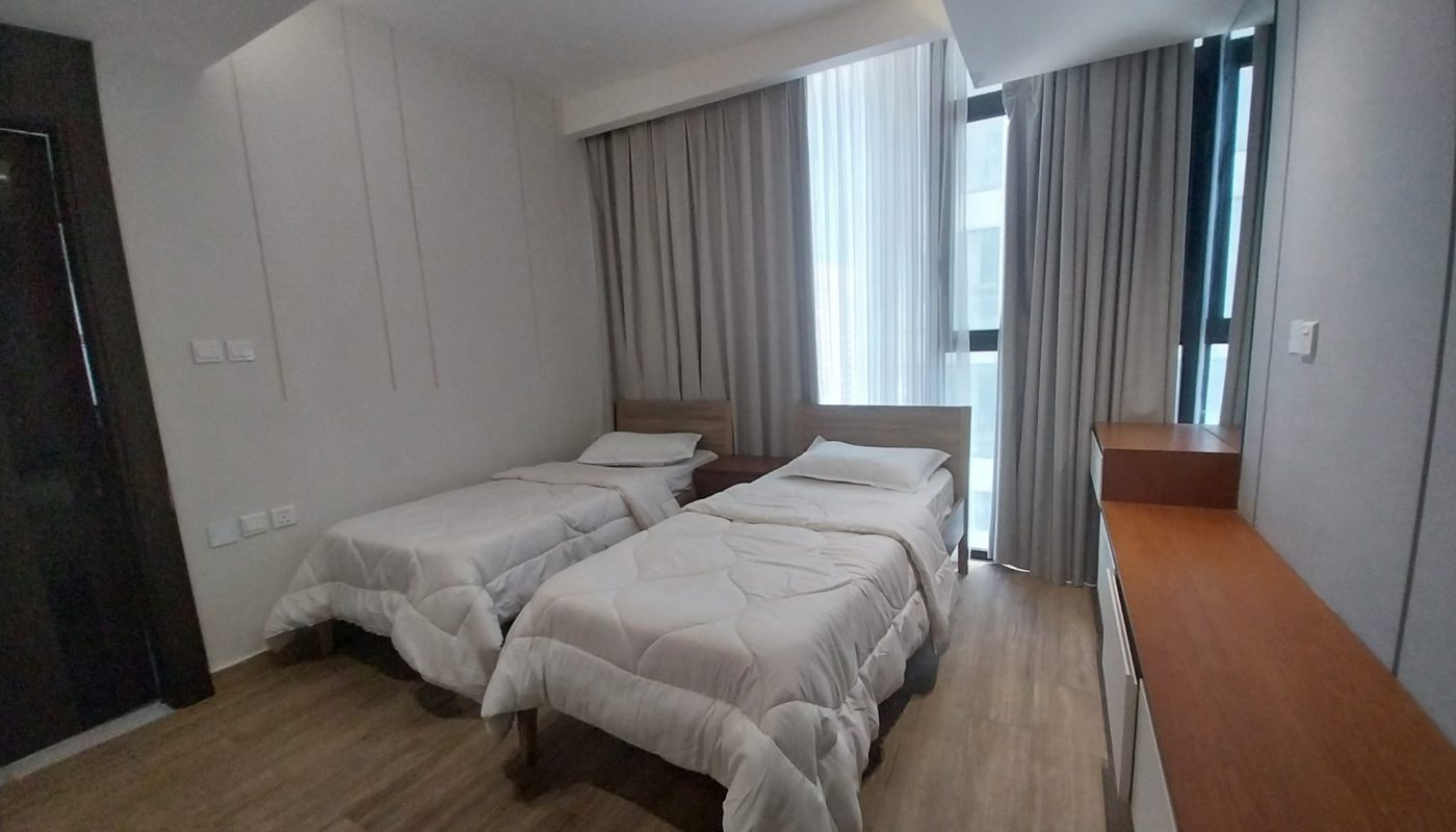 A modern bedroom with two single beds, white bedding, light wood furniture, a dresser, large window, and gray curtains.