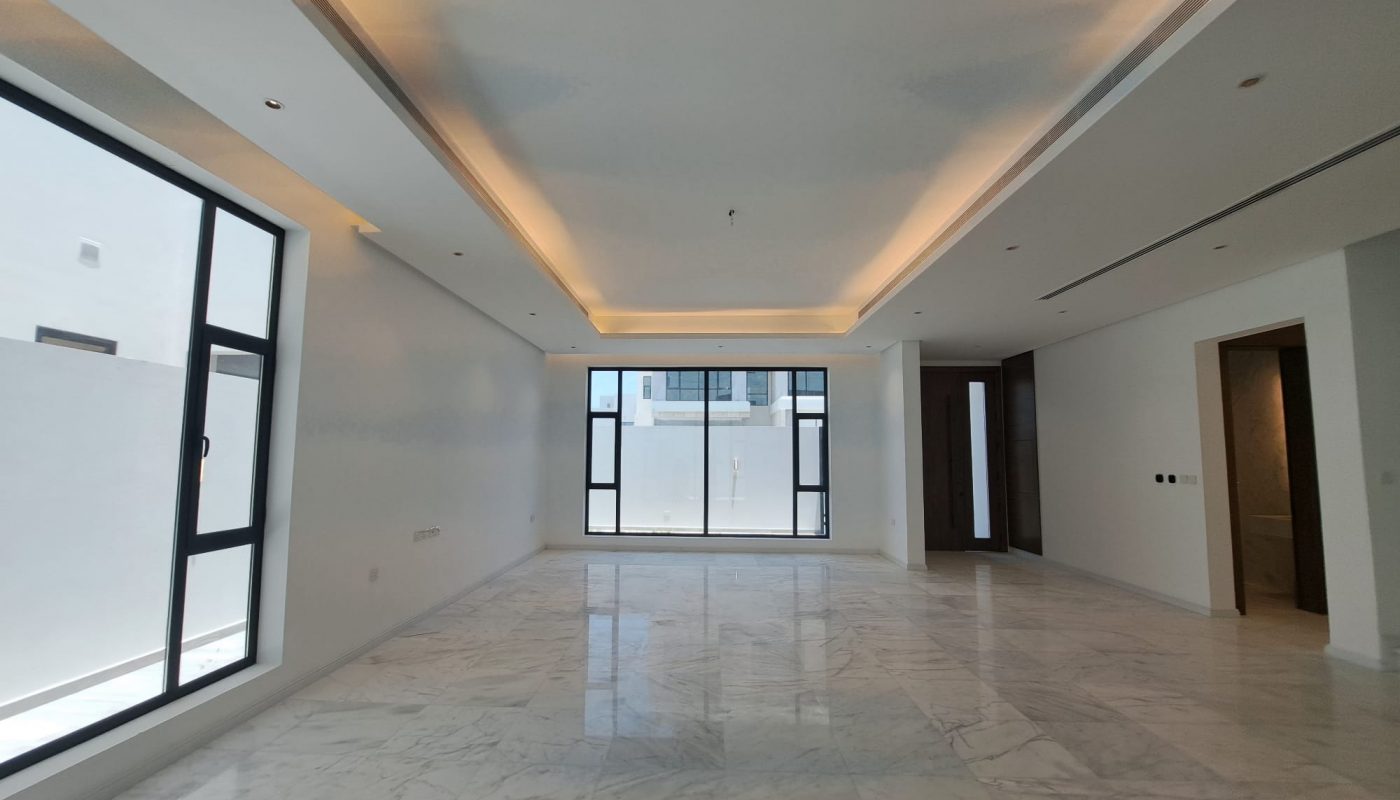 Spacious empty room with marble flooring, recessed ceiling lights, large windows, and white walls.