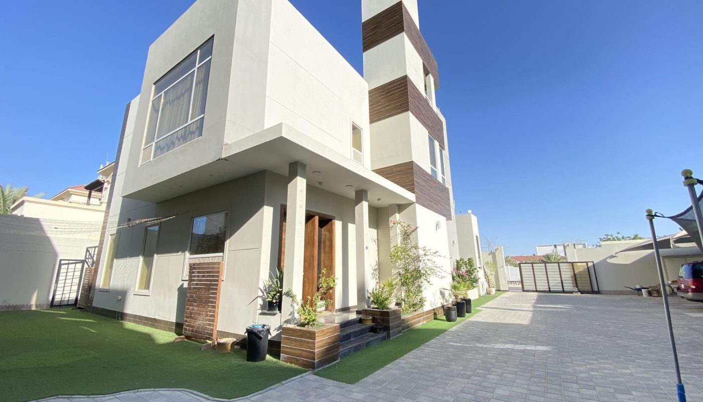 A modern residential compound consisting of three villas located in Al Janabiyah, surrounded by a lush green lawn.