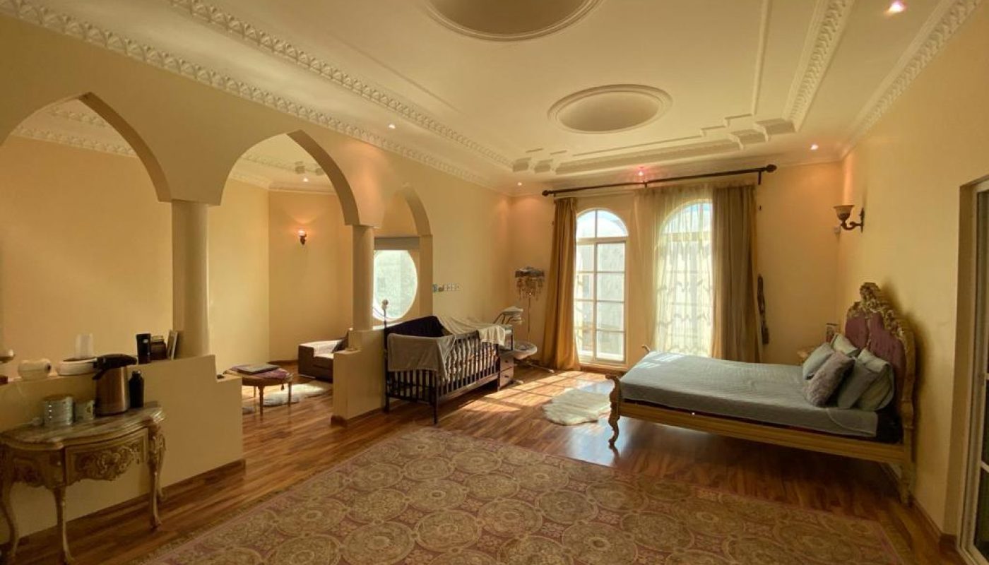 A villa bedroom with an arched doorway and a furnished bed.
