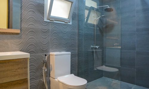 A modern bathroom with a glass shower and toilet located in a great location.