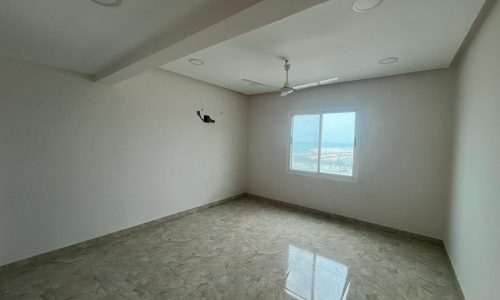 Apartment for rent: Empty room with tiled floor, a large window providing natural light, in the Galali area, and a ceiling fan.