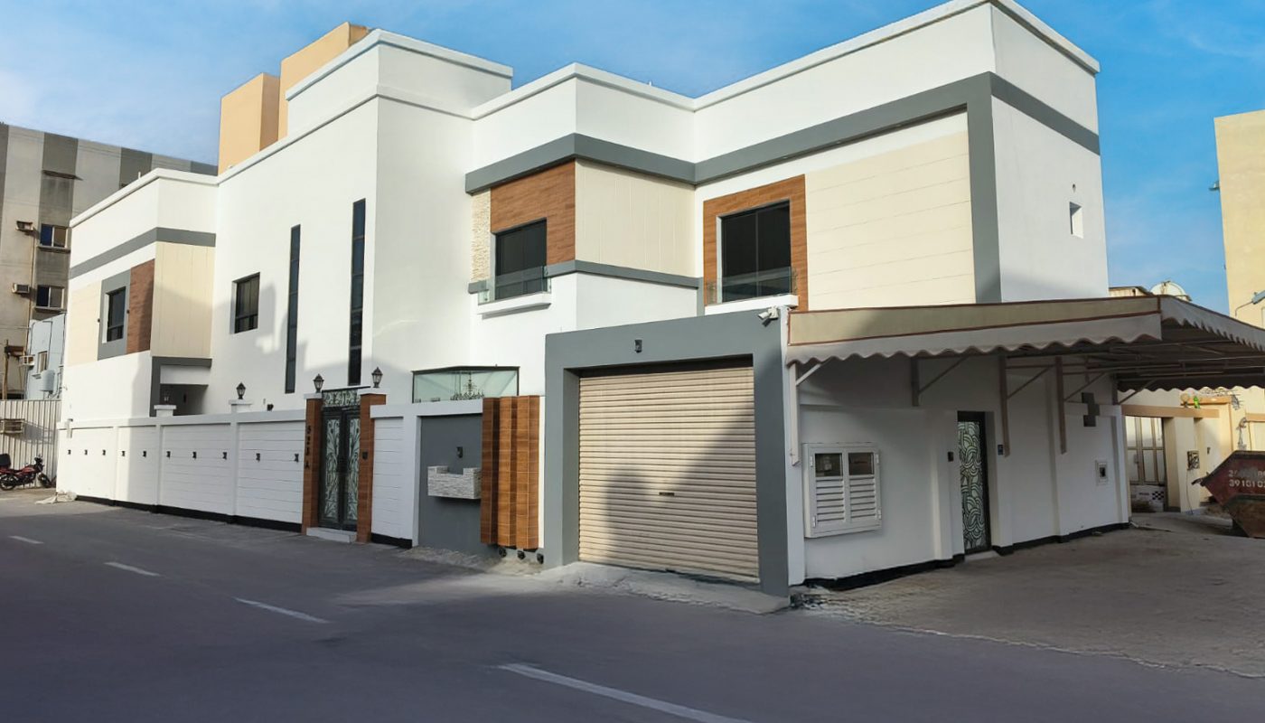 A modern two-story white house with flat roofs, garage, and a covered parking area on a clear day.