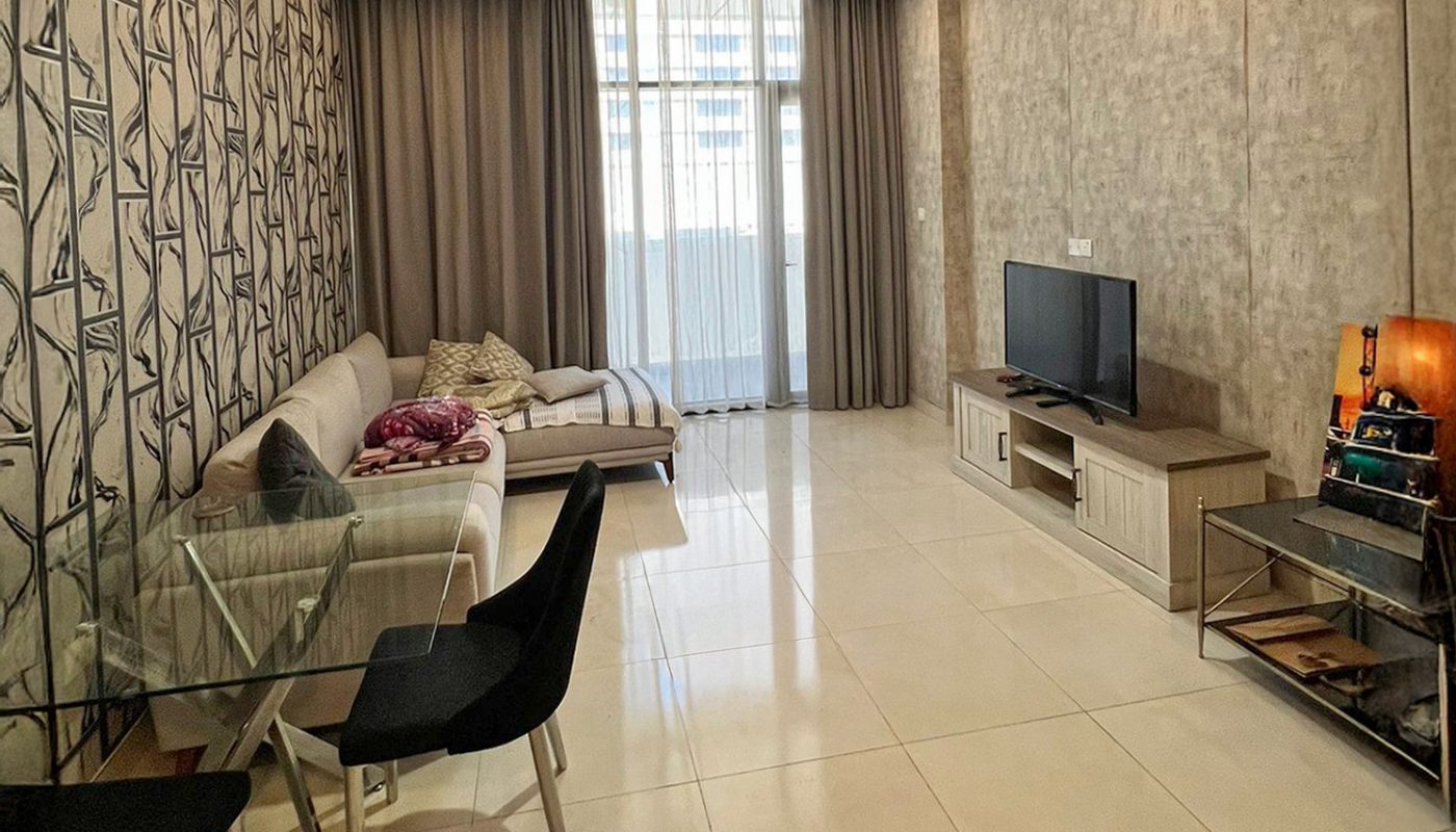 Modern living room with tiled floors, a white sectional sofa, glass dining table with two chairs, TV on a stand, and floor-to-ceiling curtains covering a large window.