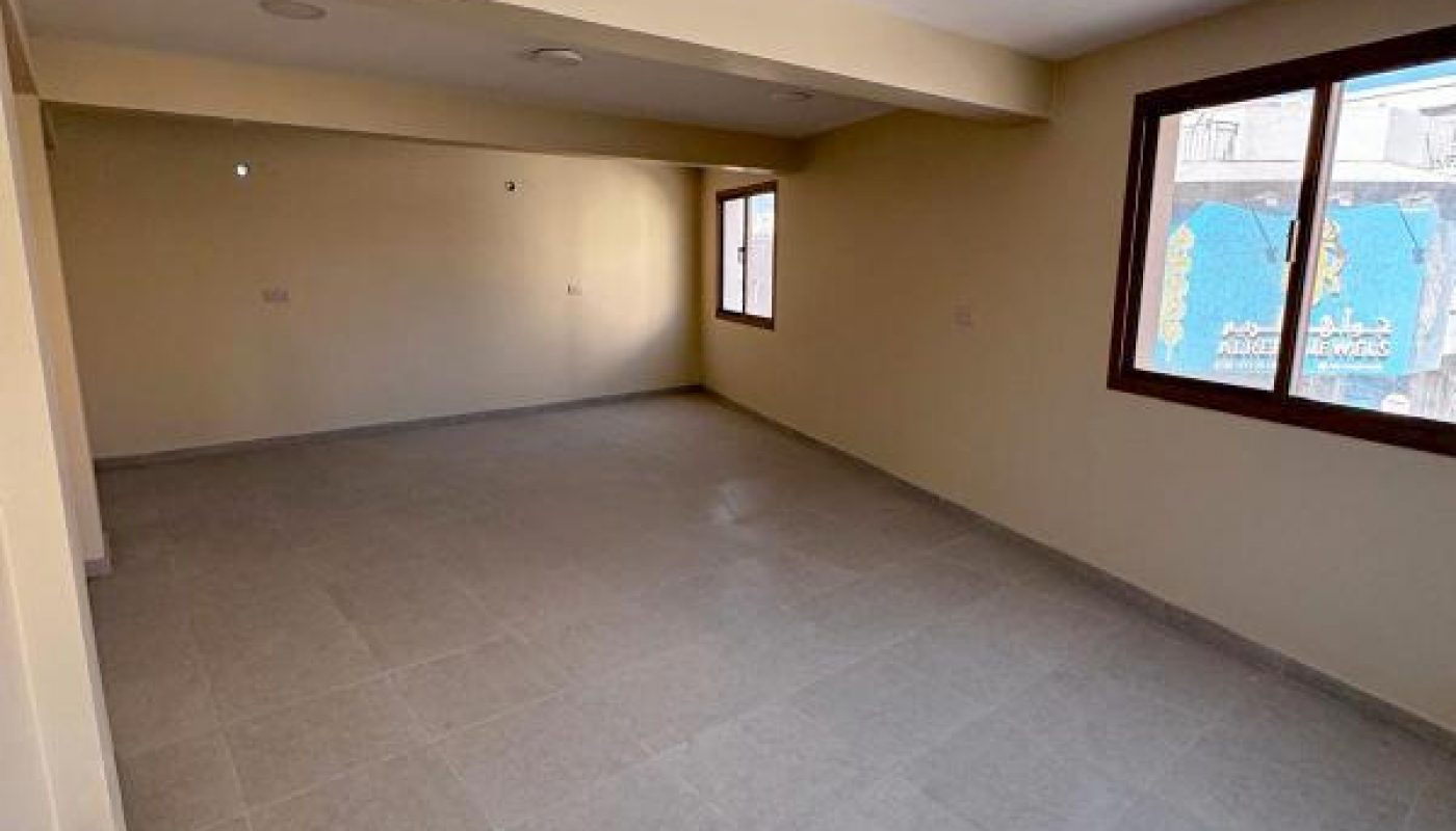 Empty room with light-colored walls and tiled floor, featuring two windows letting in natural light.