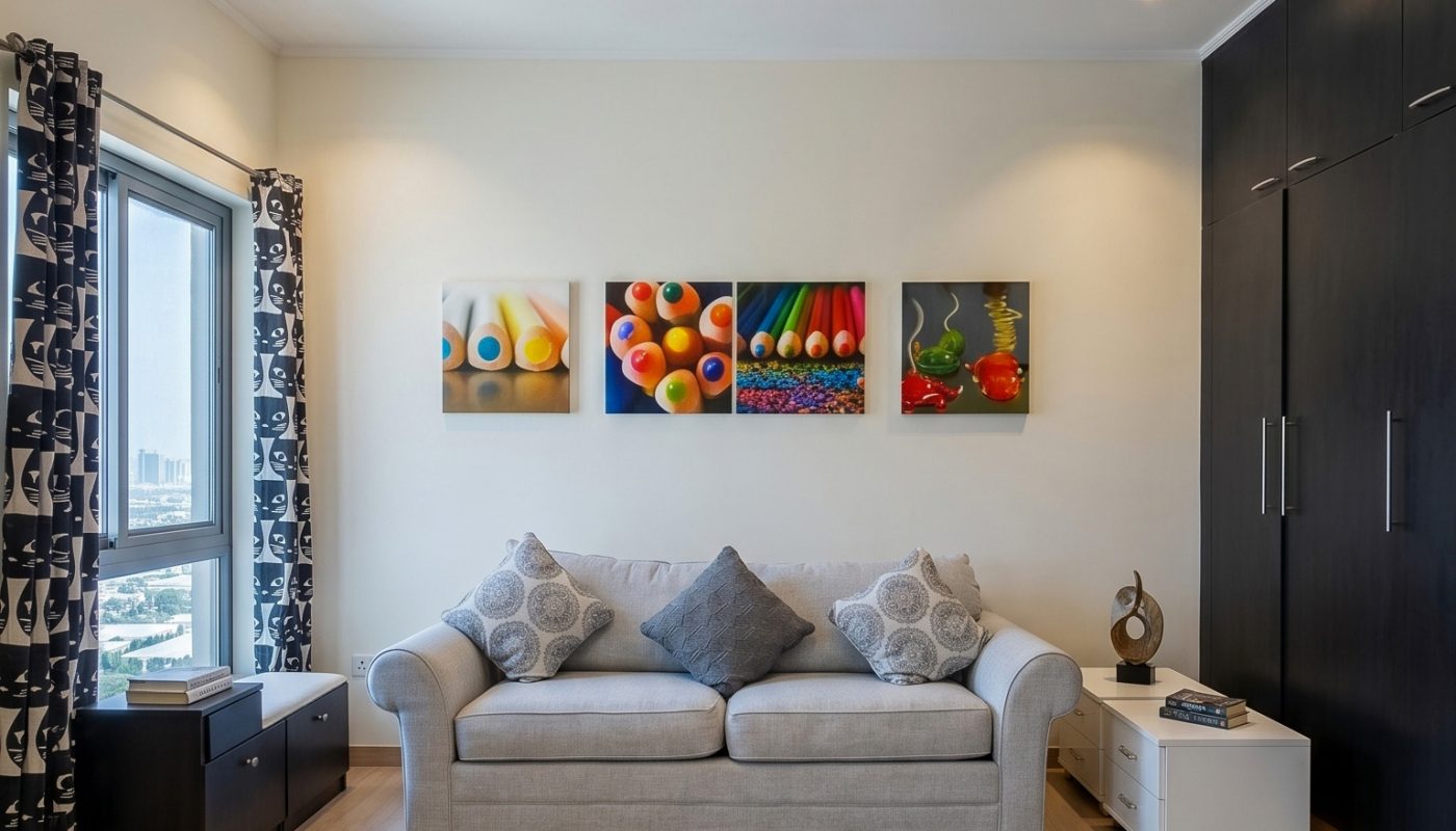 Modern living room with a light gray sofa, decorative cushions, colorful fruit-themed artwork on the wall, wooden floor, and contemporary lighting.