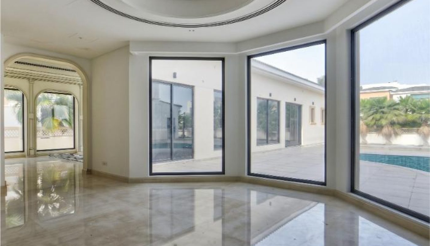 Spacious, empty room with large floor-to-ceiling windows, marble flooring, round ceiling design, and view of an outdoor pool and patio area.