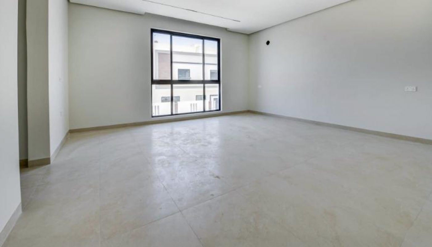 An empty, modern room with light-colored tiled flooring and large windows.