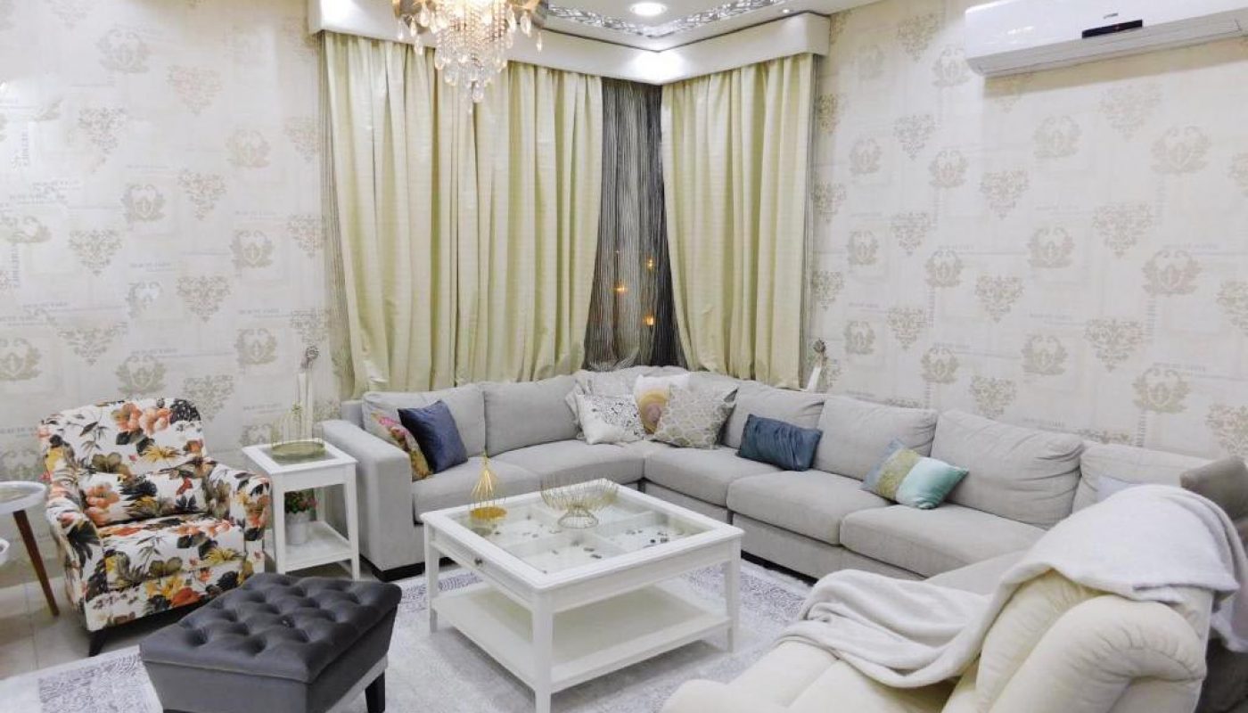 A luxury living room with white furniture and a chandelier in a 3BR apartment in Isa Town.