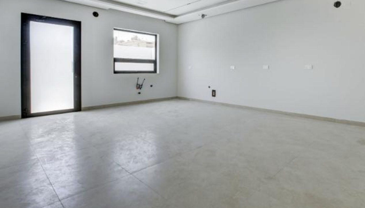 Empty, modern room with a glass door, a window, and light gray tiled floors.