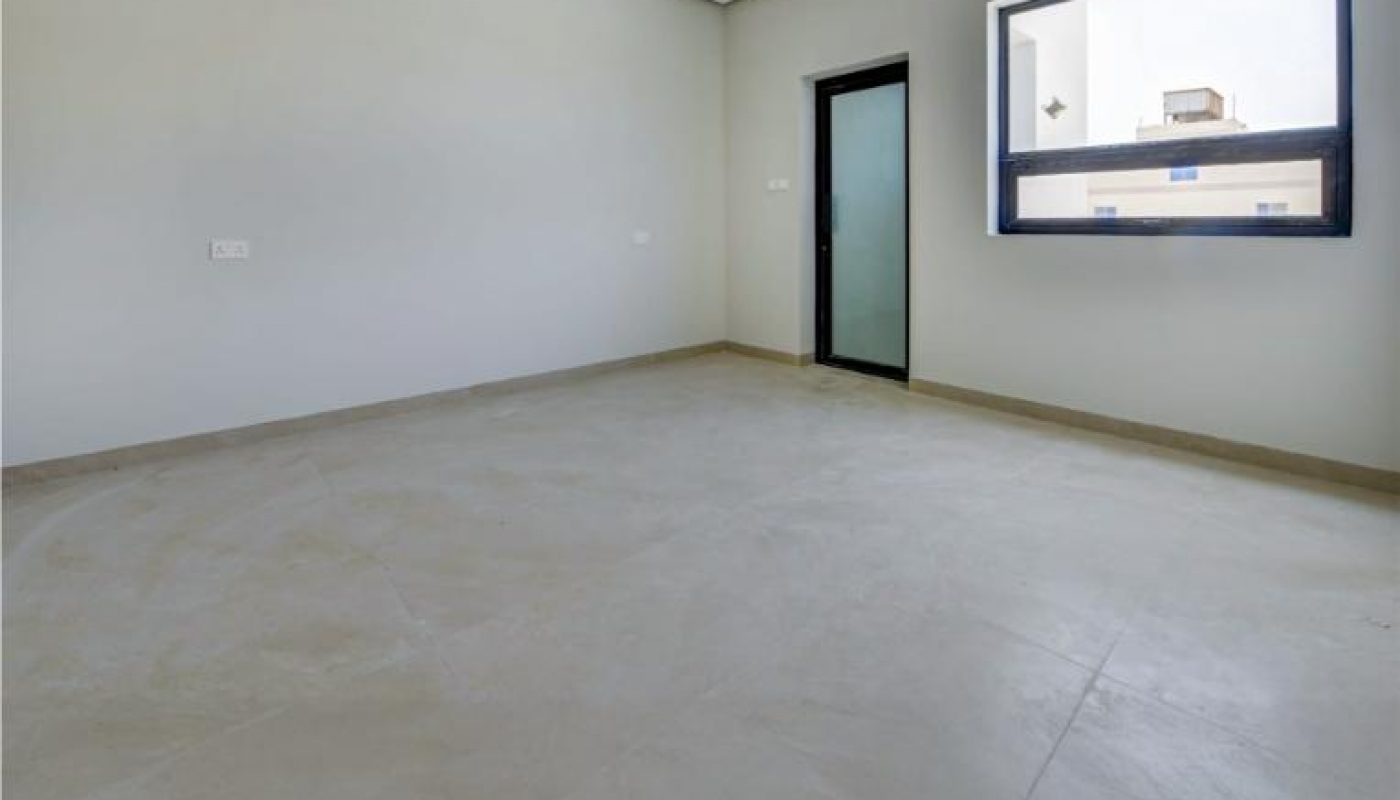 An empty room with light gray walls, beige tiled floor, a glass door, and a large window.