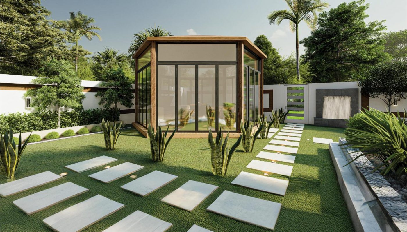 A modern glass-walled garden room stands in the center of a yard with neatly trimmed grass, stone stepping paths, and surrounding plants and trees.
