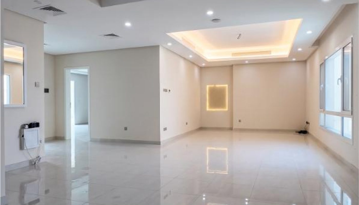 Spacious, empty modern living room with white tiled floor, recessed ceiling lights, large windows, and neutral-colored walls.