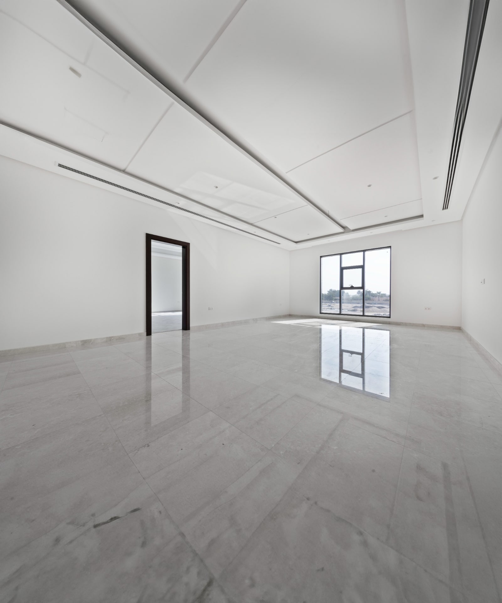 Spacious empty room with white walls, large window, and marble floor, with a single open doorway on the left side.